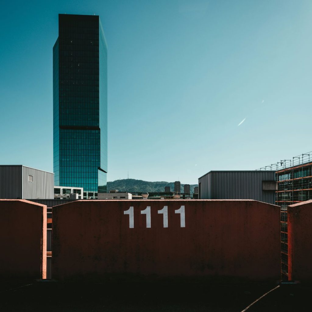 Änglanummer 1111 på en parkeringsplats-skylt med vacker utsikt över staden och en klarblå himmel.